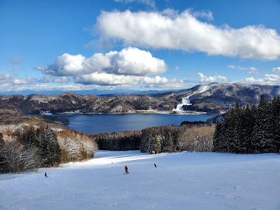 Wintersports enthusiasts enjoying the snow-covered slopes at Sun Alpina Hakuba Sanosaka Snow Resort in Japan, complete with stunning winter scenery and a charming chalet.