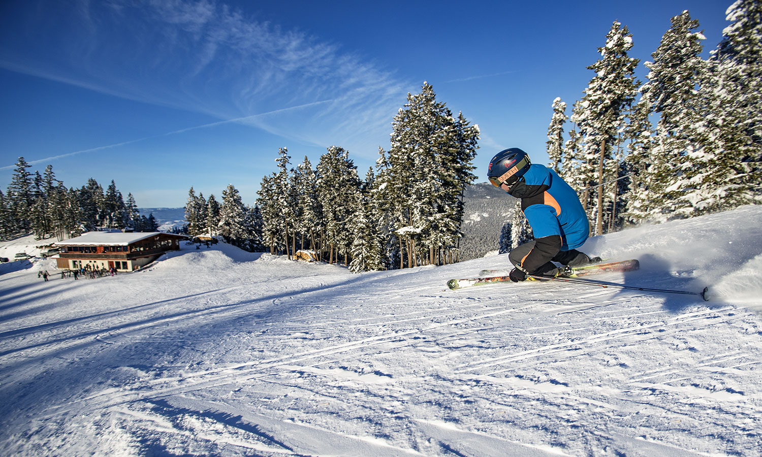 Harper Mountain in Canada - a man riding a snowboard down a snow covered slope.