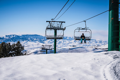 A picturesque view of Pine Creek in Cokeville Wyoming with a ski lift in the foreground part of a ski resort. A lone skier can be seen in the beautiful winter landscape.