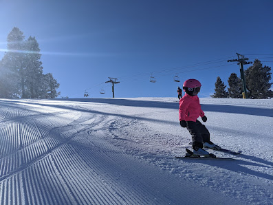 A skier participating in winter sports at Pine Creek in Cokeville, Wyoming. A child can be seen learning to ski in the serene, snowy landscape of the ski resort.