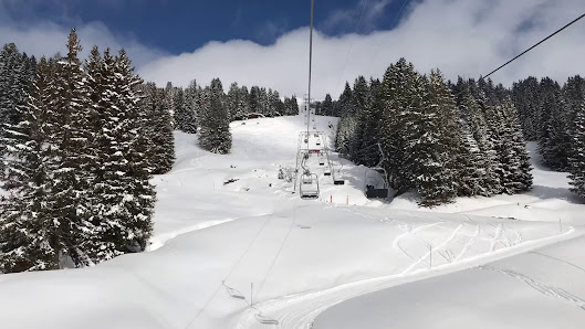 A ski resort in Sportbahnen Hochwang Arosa featuring a skier on snow-covered slopes taking a ski lift up for another thrilling winter sports run down the mountain.