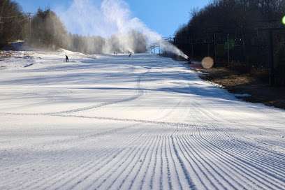 A winter sports scene at Berkshire East in Charlemont Massachusetts featuring a skier gliding down snow-covered slopes. A ski lift is visible underlining the ambiance of a ski resort.