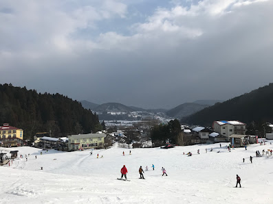 Image depicting a bustling ski resort in Okukan, Kansai, Japan, accented by a picturesque winter landscape painted with a blanket of snow under clear blue skies.