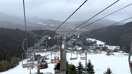Ski resort in Okukan, Honshu, Japan, featuring a winter sports scene with skiers. A ski lift cuts through the idyllic winter landscape under a clear sky.