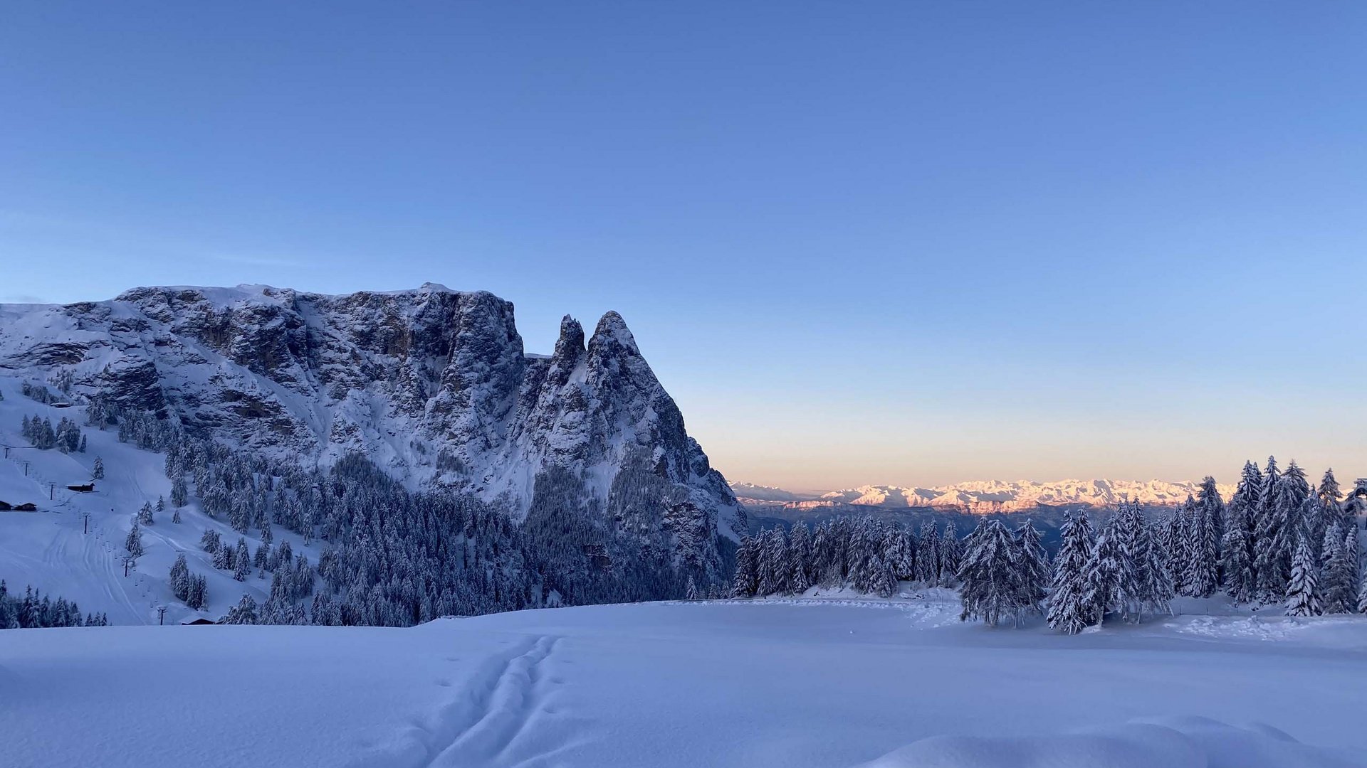 Breathtaking winter landscape at Alpe di Siusi in South Tyrol, Italy. Majestic snow-capped mountain peaks under a clear blue sky and skiers enjoying the pristine conditions.