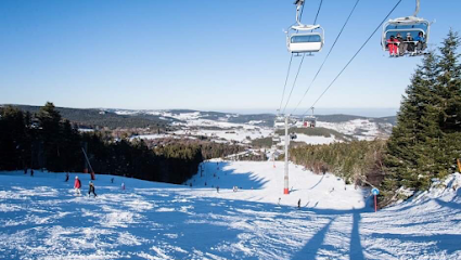 Winter scene at Chalmazel ski resort in France, showing active ski slopes with a ski lift and a cozy challet nestled amongst the snow-covered landscape.