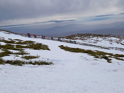 A bustling winter sports scene at Ski Sierra Bejar Covatilla in Salamanca, Spain. A chalet overlooks the winter sports center surrounded by stunning winter scenery.