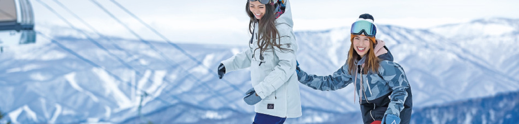 Marunuma Kogen in Japan - two girls are holding hands while standing on a snowboard.