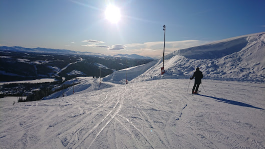 A skier descends a snowy slope in Åre Duved Northern Sweden with visible ski lifts and the surrounding ski resort embodying an active winter sports scene.