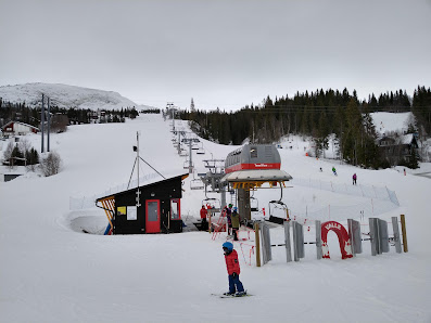 Ski resort scene at Åre Duved in Jämtland, Northern Sweden, featuring ski lifts ascending over a rich winter sports landscape; chalet barely visible in the distance.