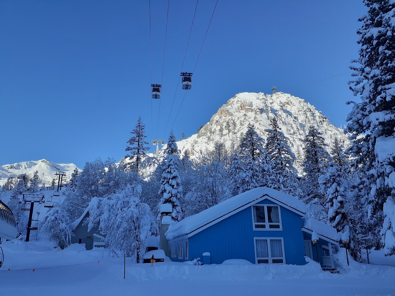 Scenic view at Palisades Tahoe, with a ski lift gently ascending spahtreous mountains at a popular ski resort, showcasing an enticing winter sports scene amidst stunning winter scenery.