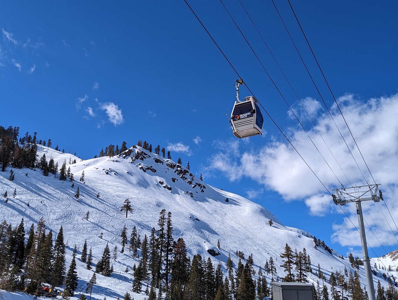 A ski lift ascends the snow-covered slopes at Palisades Tahoe a ski resort in Lake Tahoe California. A skier carves a path through the winter sports scene.