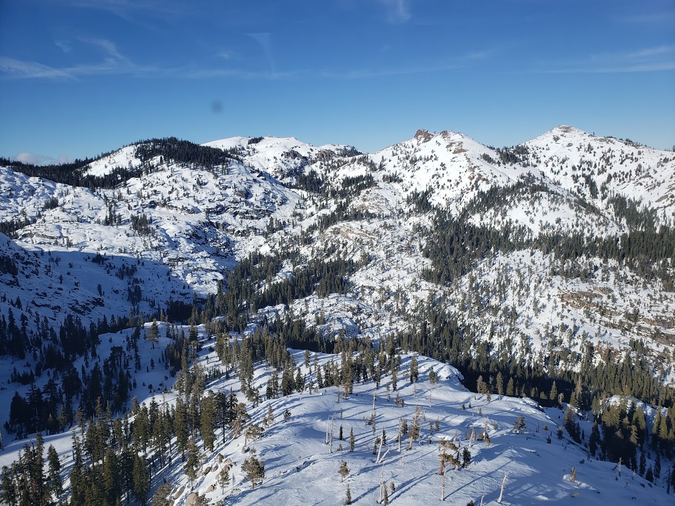 Winter sports enthusiasts taking advantage of a beautiful day at Palisades Tahoe in Lake Tahoe, California, effortlessly navigating the snow-covered slopes with ski resort facilities and a ski lift in the background against a stunning mountain backdrop.