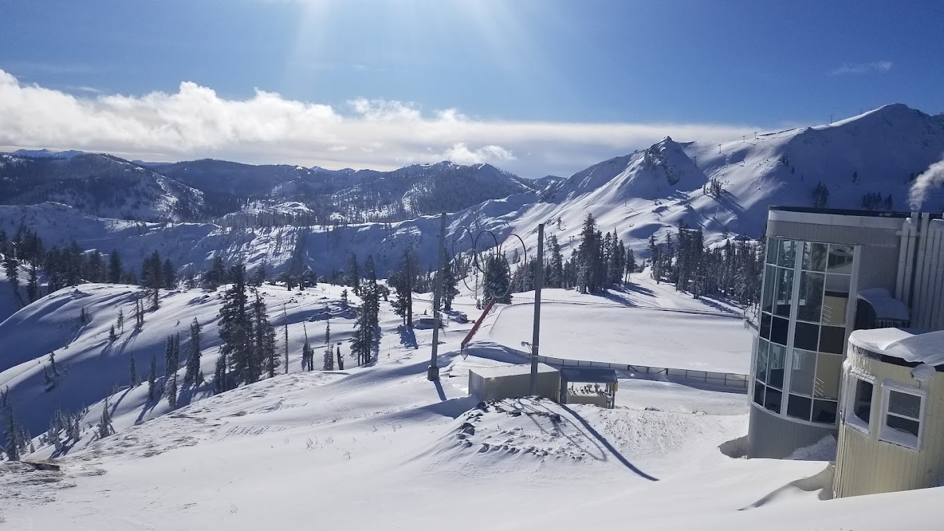 Skier gliding down the snow-covered slopes at Palisades Tahoe ski resort, Lake Tahoe, California. Ski lift cables stretch above, highlighting a vibrant winter sports scene.