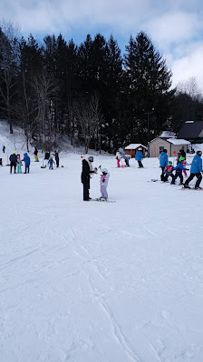 Winter sports scene at Kissing Bridge in Greater Niagara, Glenwood, New York, featuring a family enjoying skiing at the resort, including a child learning to ski.
