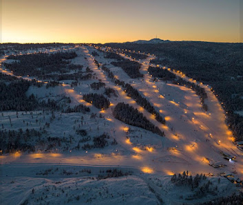 Winter sports scene at Skimore Kongsberg in Norway featuring a ski resort with beautiful stanning winter scenery, including a cozy challet nestled among snow-covered trees.