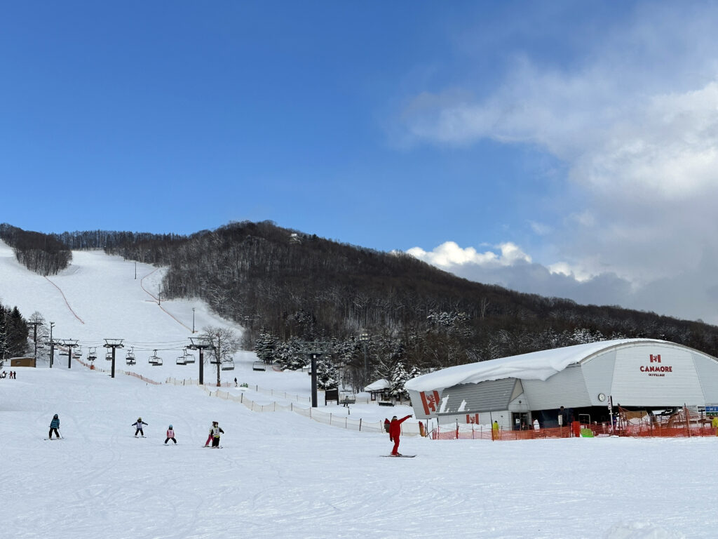 Canmore Ski Village – Higashikawa in Japan - a group of people skiing down a snowy slope.