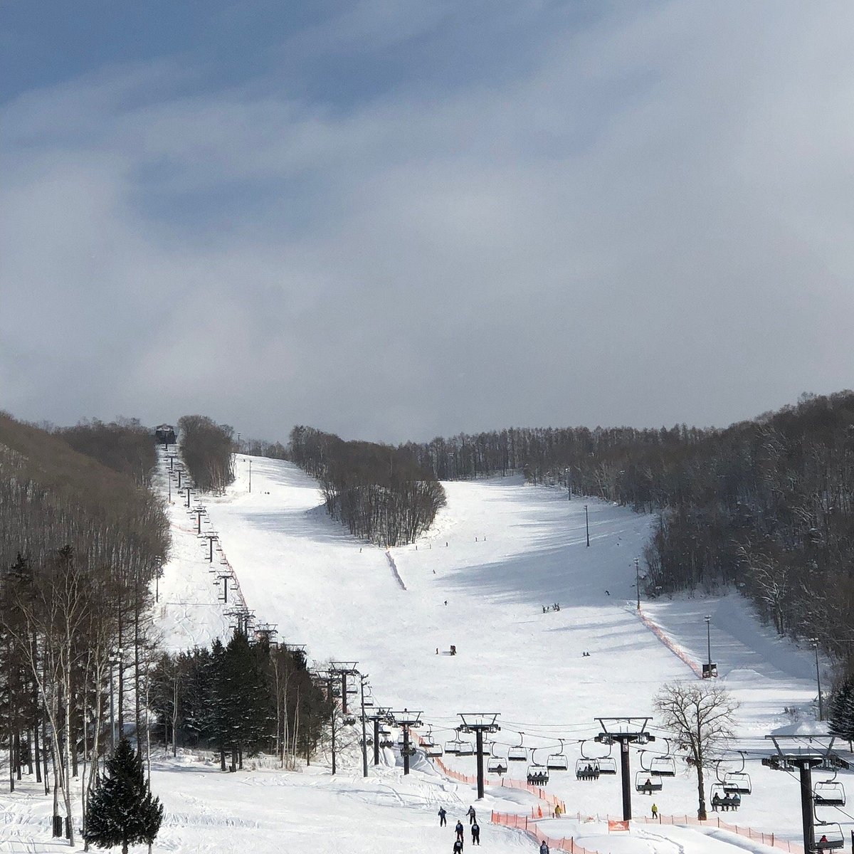 Canmore Ski Village – Higashikawa in Japan - a group of people skiing down a snowy slope.