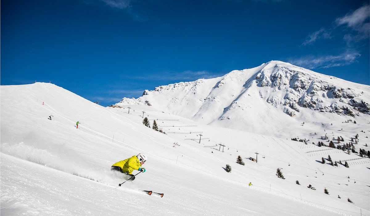 Ski Center Latemar in Italy - a person riding a snowboard down a snowy slope.